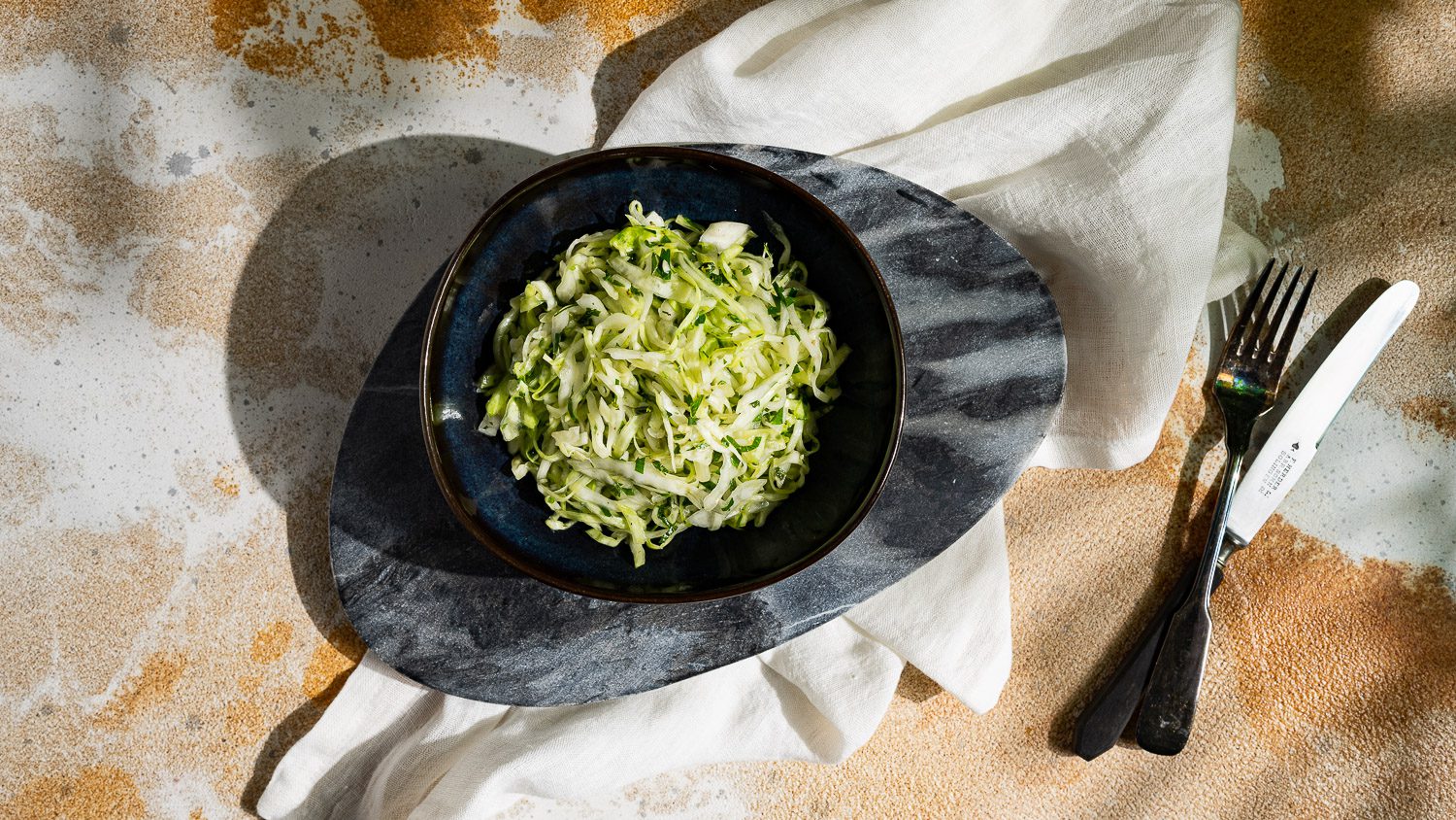 Coleslaw mit frischen Kräutern in einer dunklen Schüssel serviert.