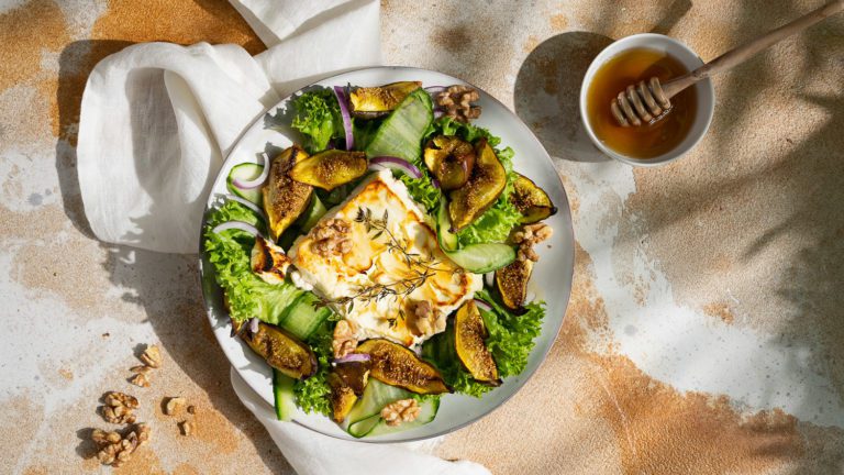 Ofenfeta mit Feigen und gerösteten Walnüsse, serviert auf Salat mit Gurken und Zwiebeln.