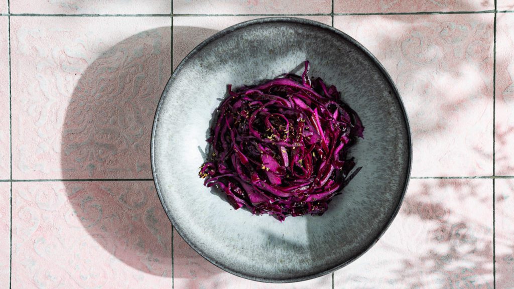 Red cabbage salad with dried mint served in a gray bowl.