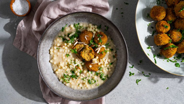 Boulettes de lentilles et de boulgour avec couscous perlé dans une sauce au yaourt, servies dans une assiette creuse