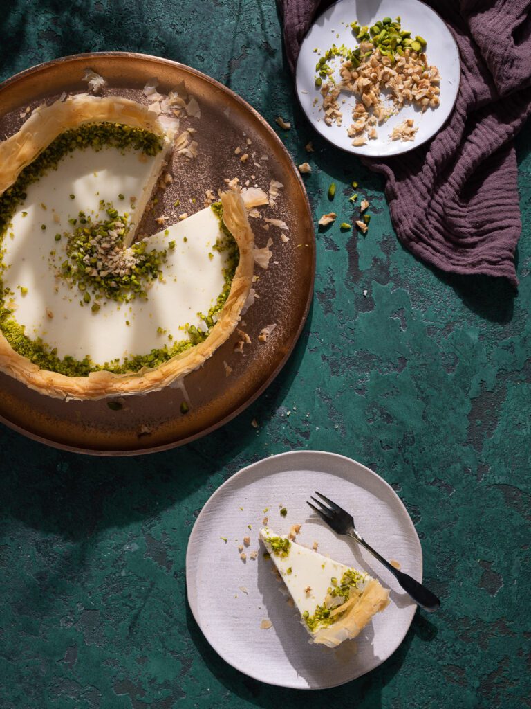 Baklava Cheesecake angeschnitten auf einem Teller. Daneben ein Stück Kuchen auf einem kleinen Teller.