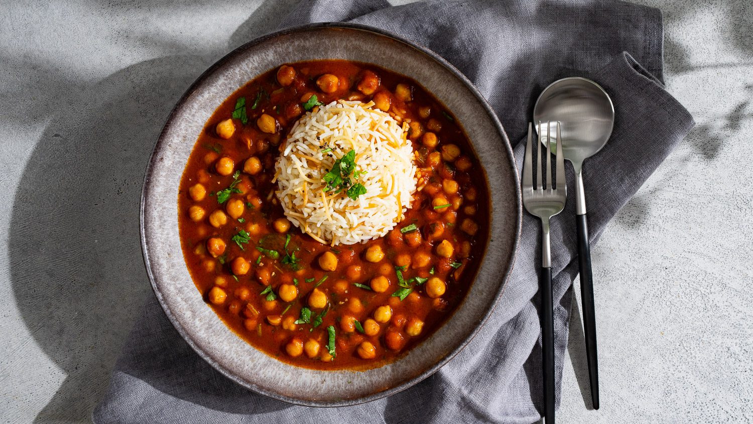 Potée de pois chiches et de riz présentée sur fond gris