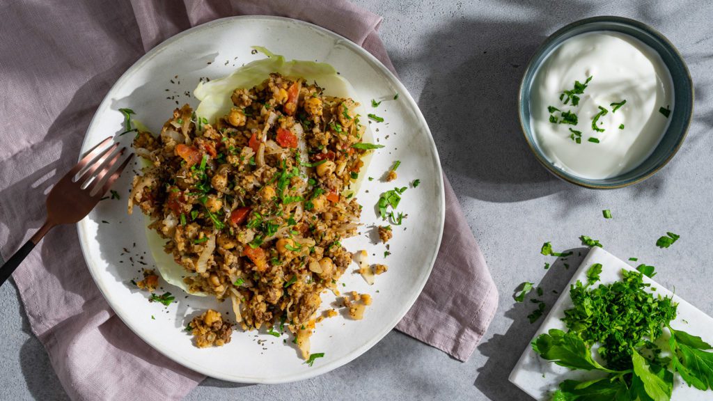 Winter Taboulé served on a white plate, pink cloth and herbs.