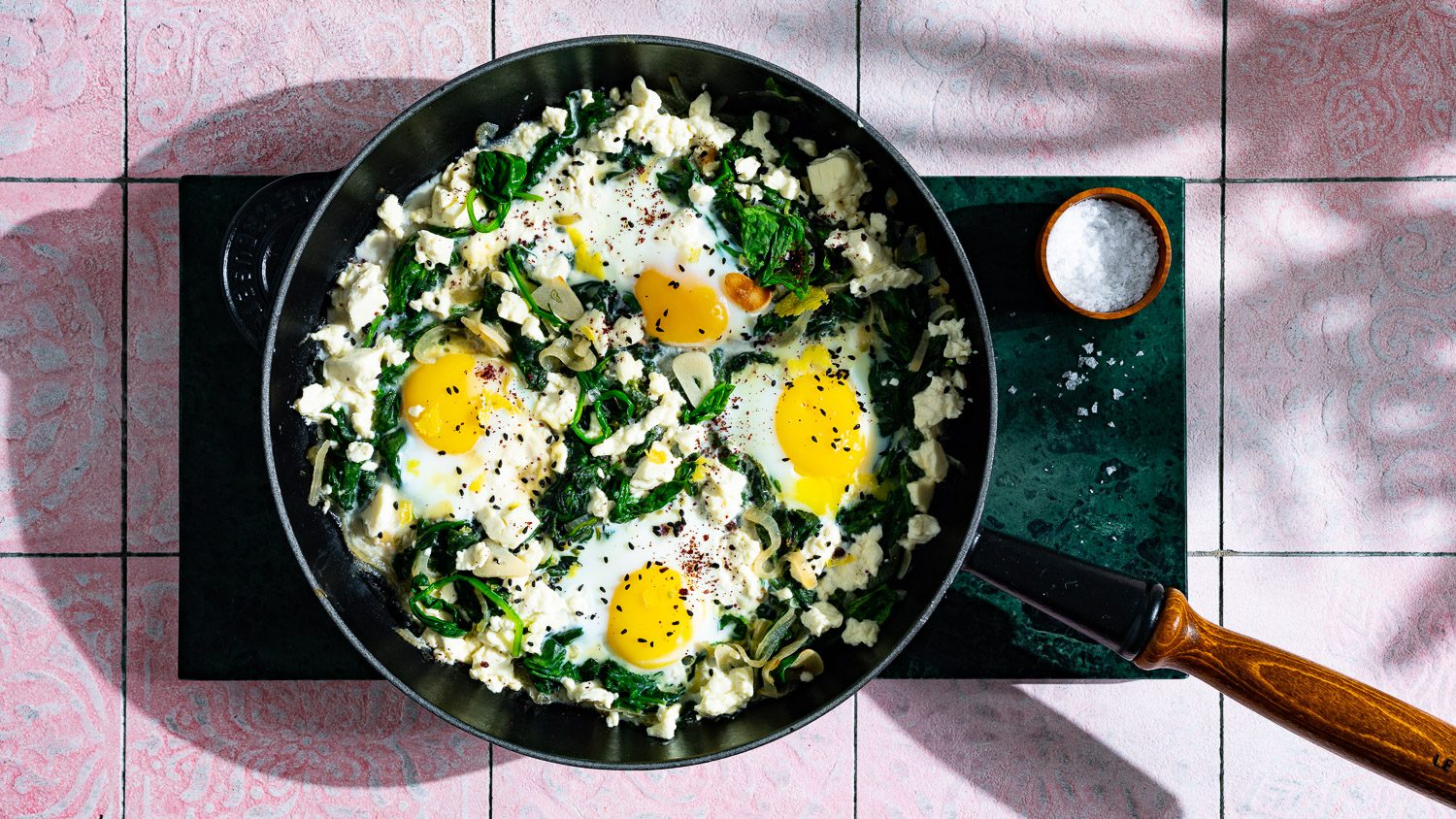 Spinat Shakshuka mit Feta ist in einer Pfanne angerichtet.