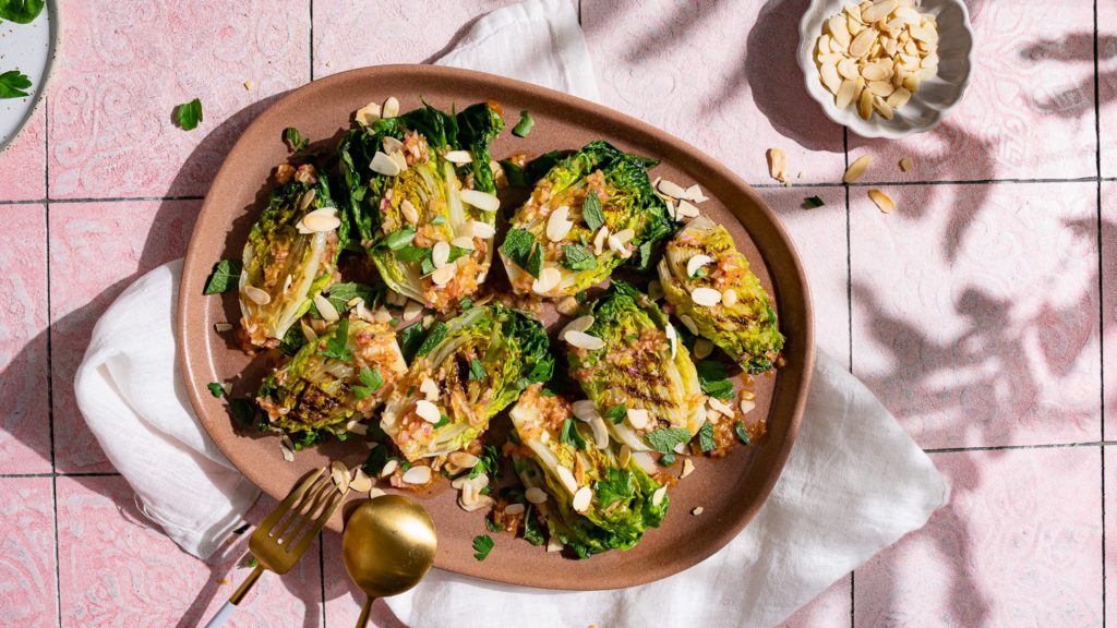 Grilled lettuce hearts with fiery vinaigrette served on a large plate.