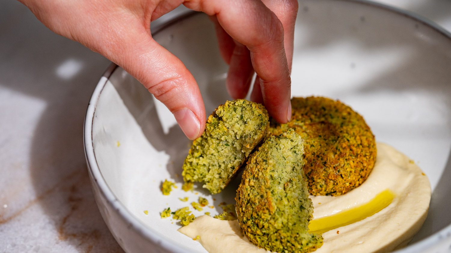 Le falafel de la friteuse à air chaud est trempé dans le houmous.