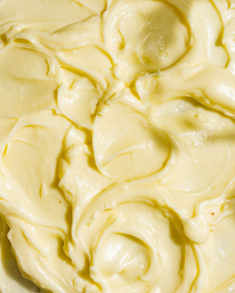 Das Frischkäse-Frosting des GEwürzkuchens von oben fotografiert. Es sieht sehr cremig aus.