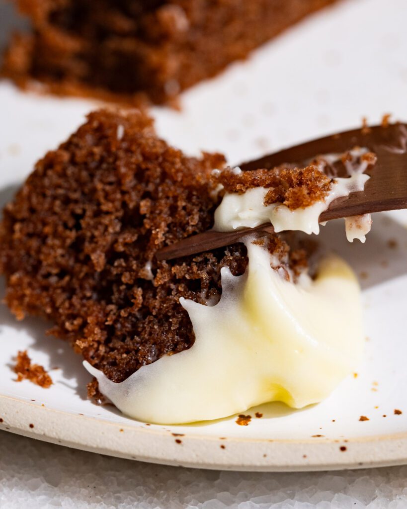 Ein Stüpck Gewürzkuchen an einer Gabel. Das Frosting sieht sehr cremig aus.