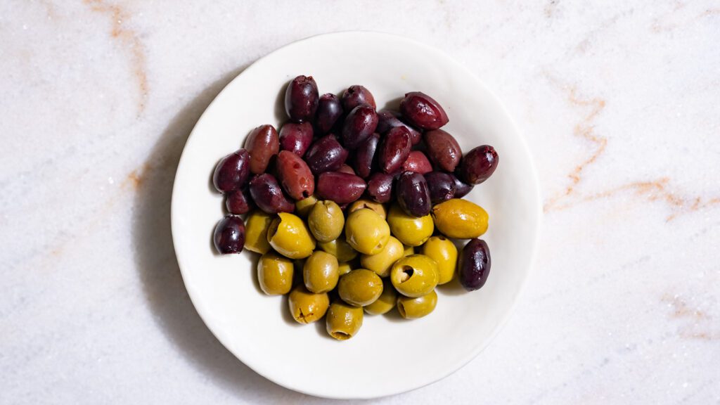 Olives Kalamata et olives vertes dans un petit bol blanc.