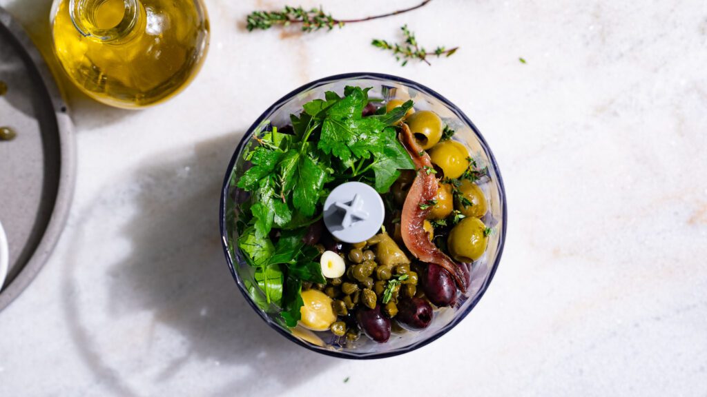 Les ingrédients pour la tapenade d'olives sont dans un petit mixeur.