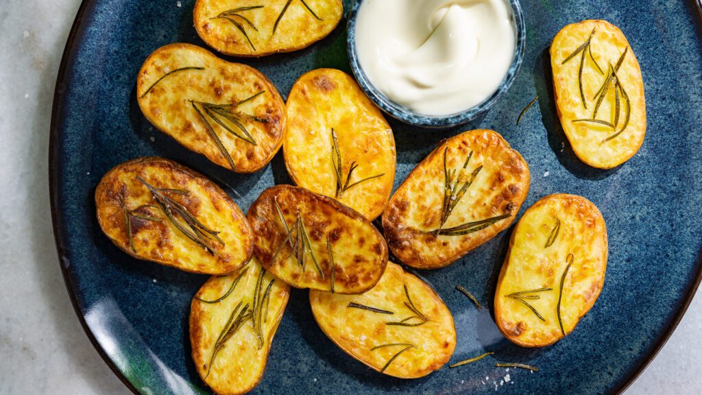 Rosemary potatoes from the hot air fryer with mayo served on a plate.