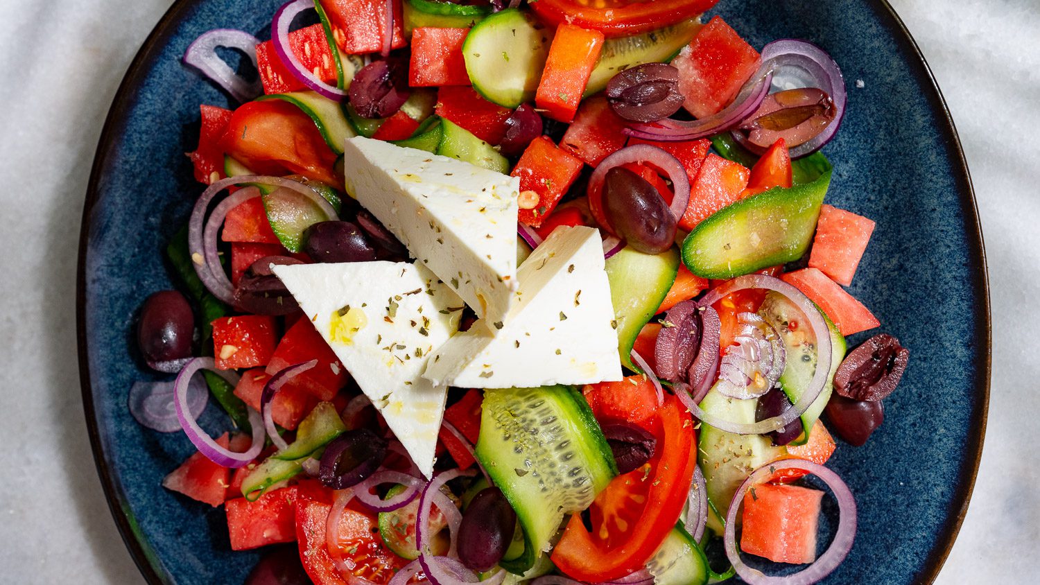 Salade grecque à la pastèque servie sur une assiette.