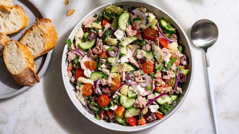 Mediterraner Thunfischsalat in einer Schüssel serviert. Daneben liegt etwas Baguette auf einem Teller.