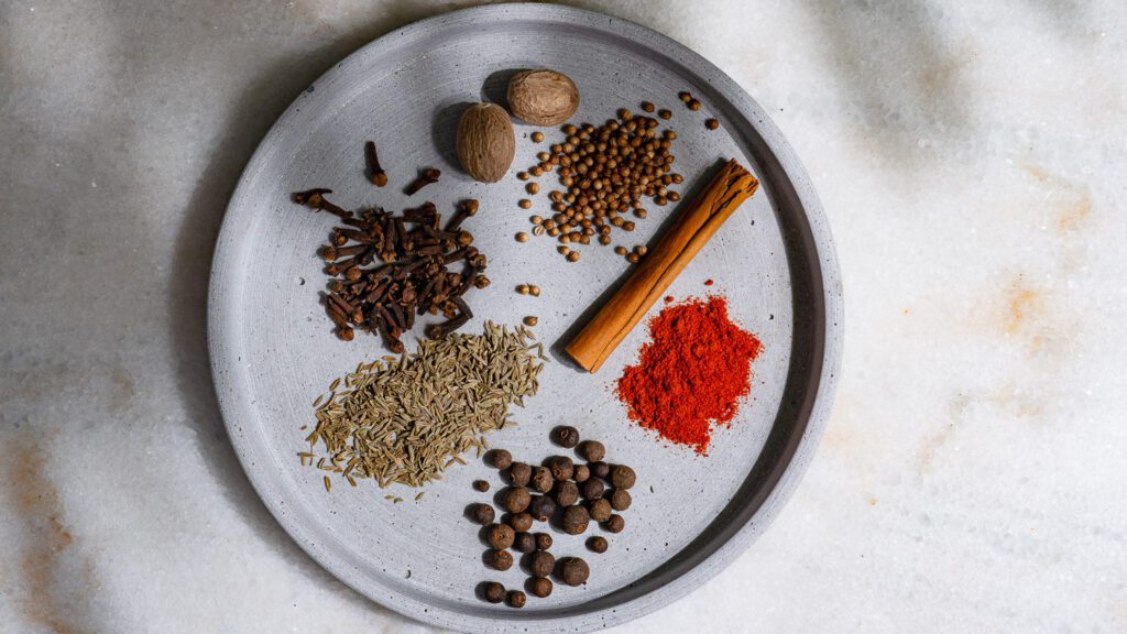 The individual spices for baharat are placed together on a plate.