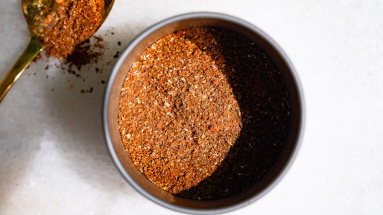 Baharat spice in a tin, with a spoon next to it.