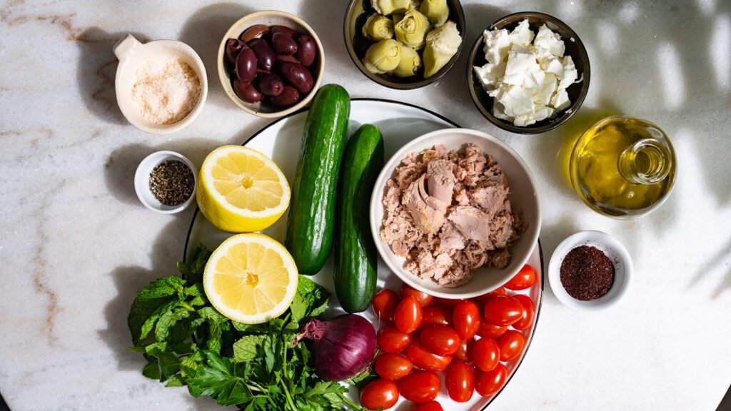 All the ingredients for Mediterranean tuna salad on one table.