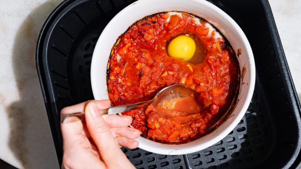 Haz un hueco en la salsa de tomate y pimiento y coloca en él los huevos.