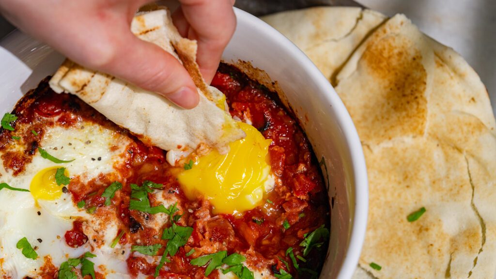 Air fryer Shakshuka is dipped in a flatbread.