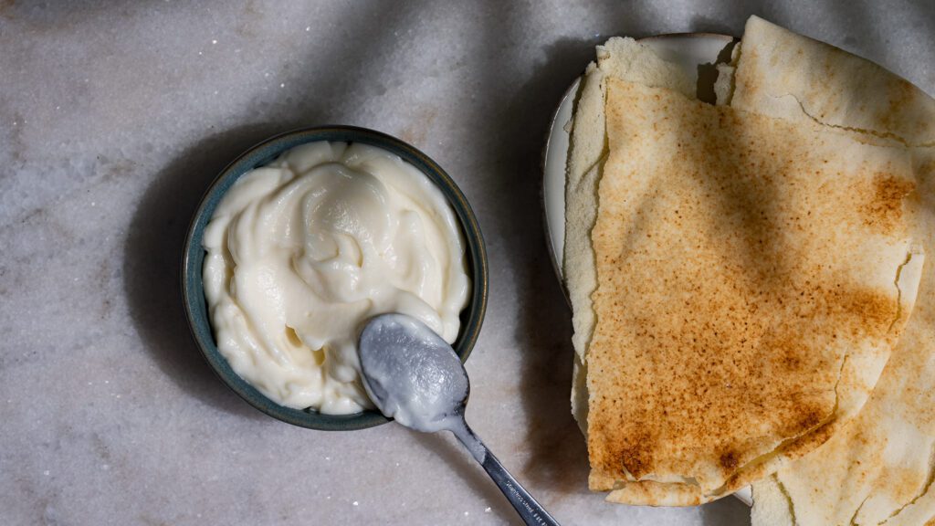 Toum está de pie sobre una mesa con pan plano.