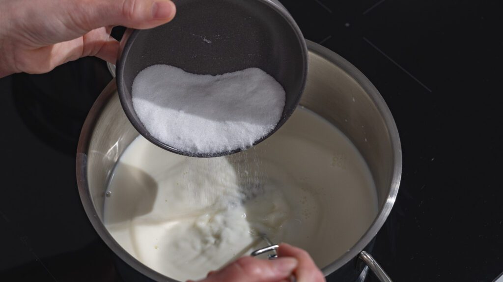 Zucker wird in Milch gerührt.