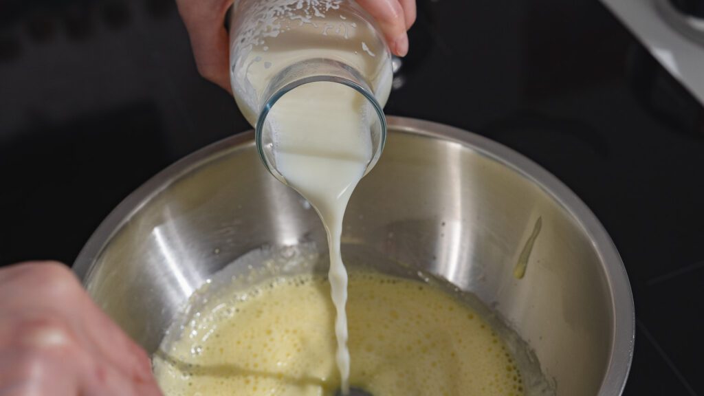 Zuckermilch wird in die Eigelb-Zuckermischung gegossen.