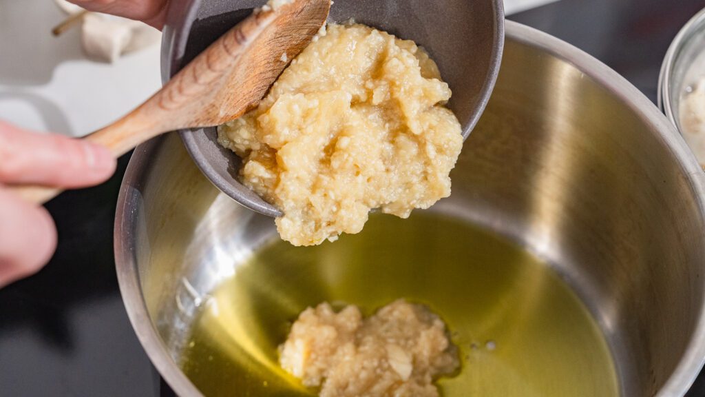 La pâte d'ail et d'oignon est mise dans une casserole avec de l'huile pour faire revenir le molokhia.