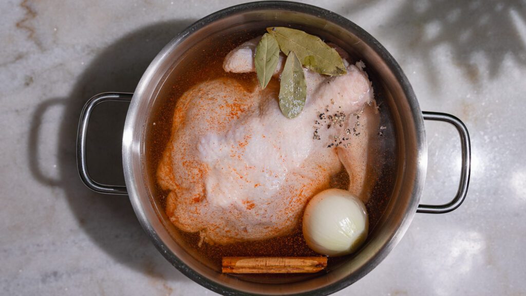 Poulet à bouillir pour molokhia avec oignon, laurier, bâton de cannelle et épices dans une marmite.