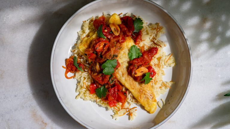 Samke Harra - scharfer Fisch in Tomatensauce mit Butterreis auf einem Teller serviert.