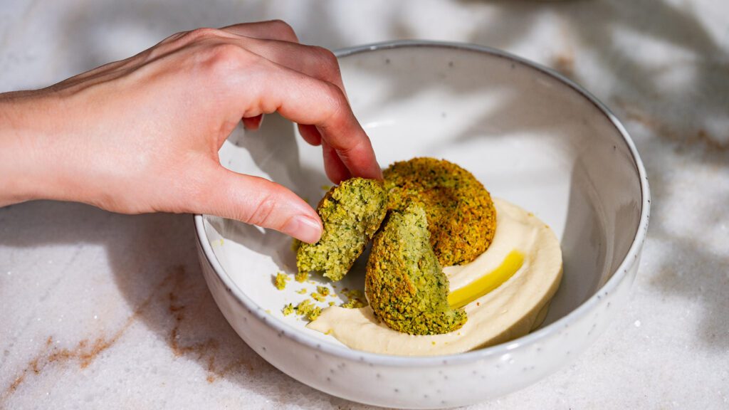 Le houmous convient parfaitement comme accompagnement des falafels. C'est pourquoi un falafel est passé à la main dans de la crème de pois chiches.