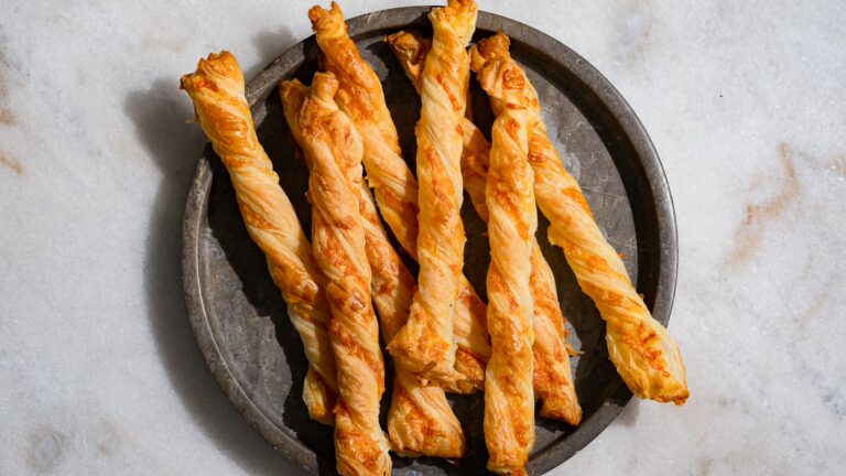 Bâtonnets de fromage en pâte feuilletée servis sur une assiette en marbre foncé.