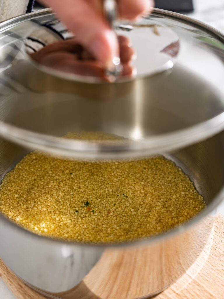 Couscous im Topf wird mit einem Deckel bedeckt.