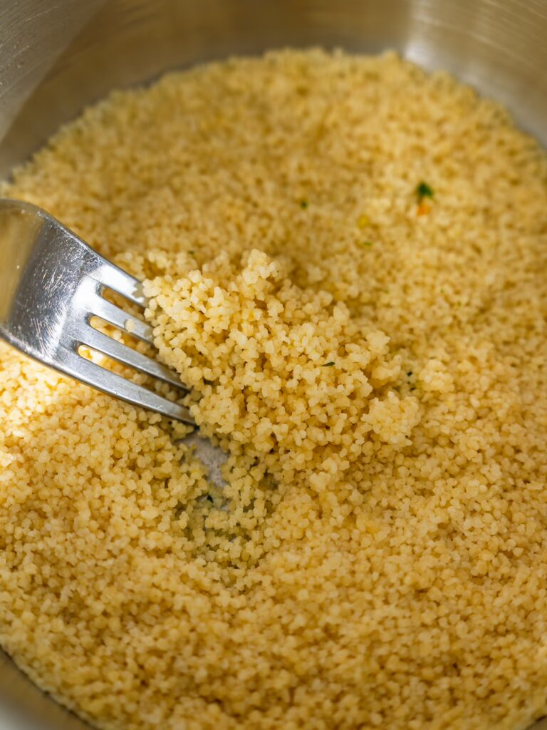 Couscous zubereiten: Couscous wird im Topf mit einer Gabel aufgelockert